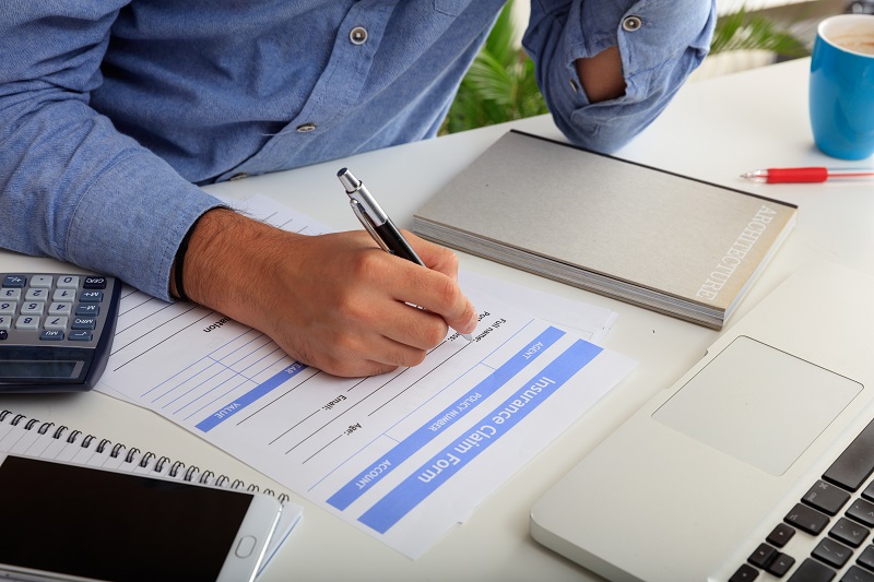 Man filling out an Insurance Claim Form in an office